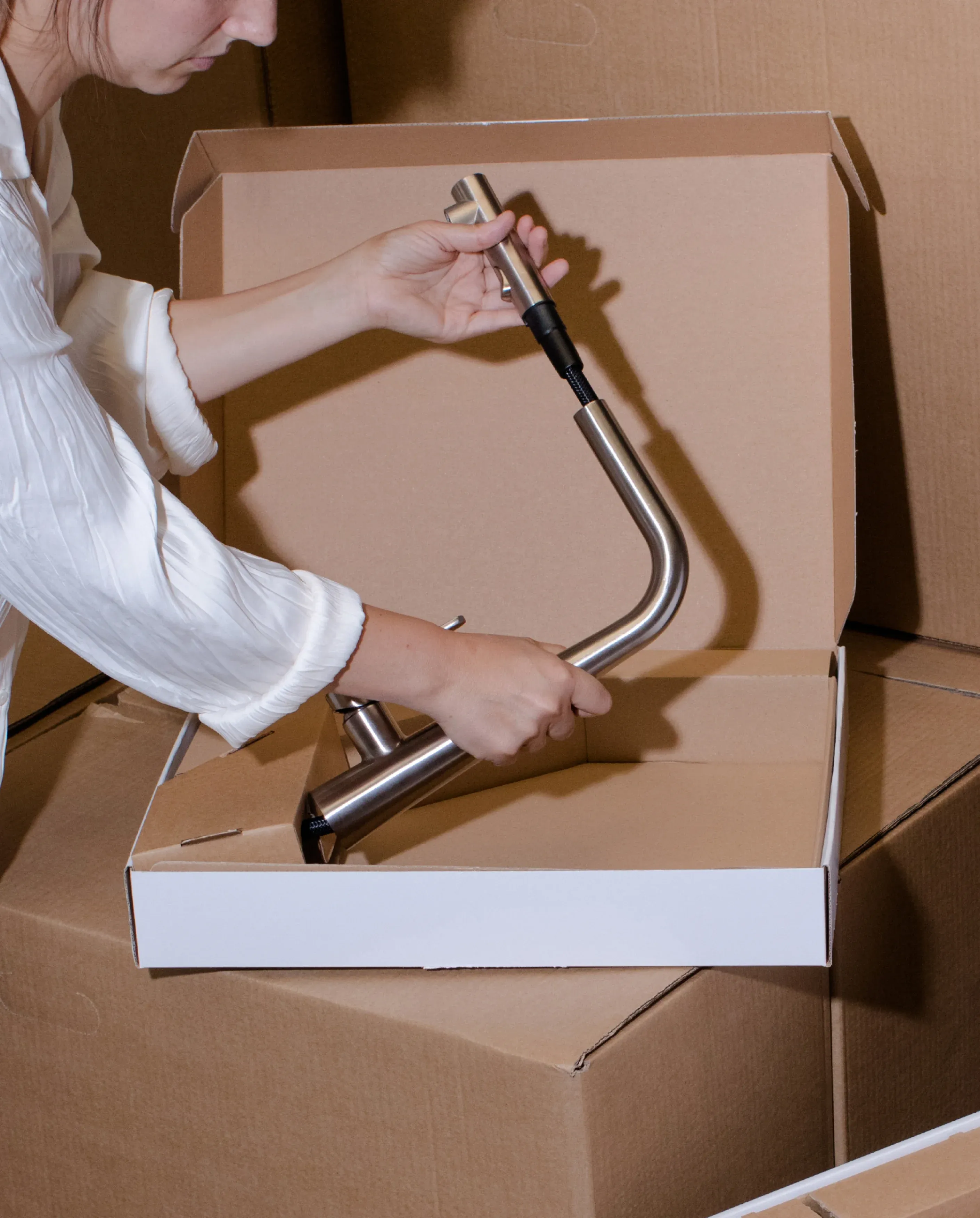 Mujer empaquetando en una caja el grifo teide shower acabo inox de ICOBEN